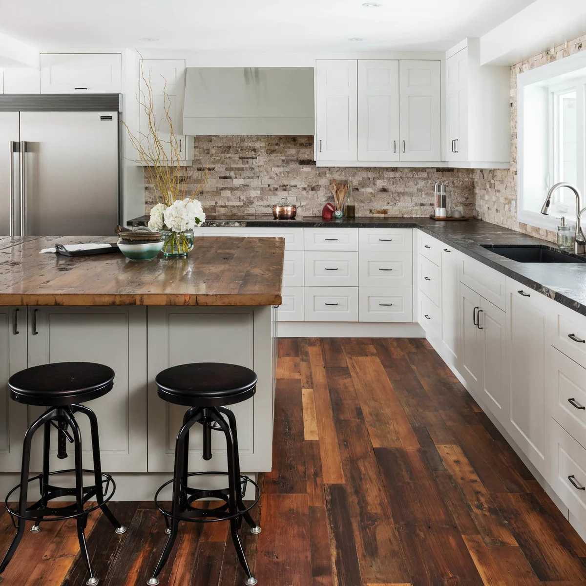 Two black round-seat kitchen stools with metal legs and circular lower foot rails