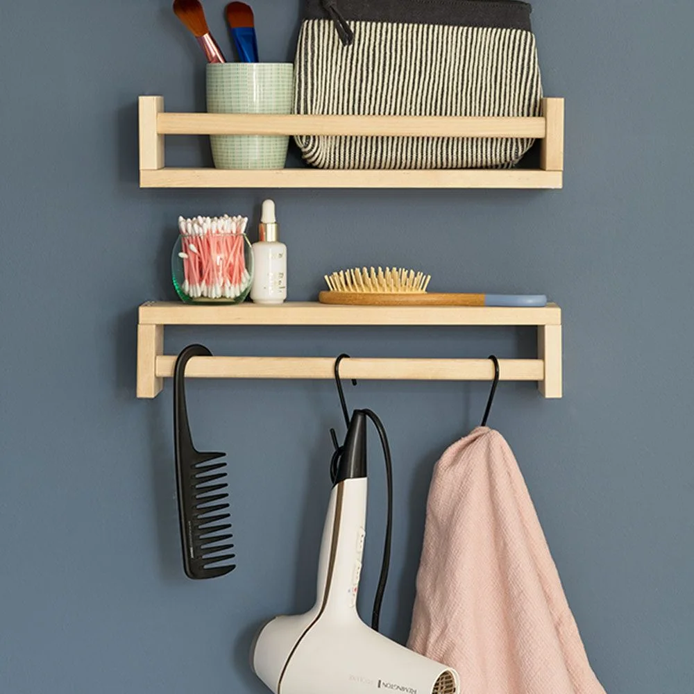 Two wooden spice racks on a blue wall holding brushes and a bag, with a comb and hairdryer hanging below