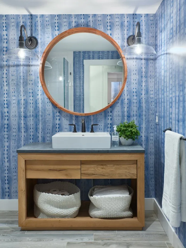 Blue patterned powder-room washstand with round wood mirror, wood drawers and lower white baskets