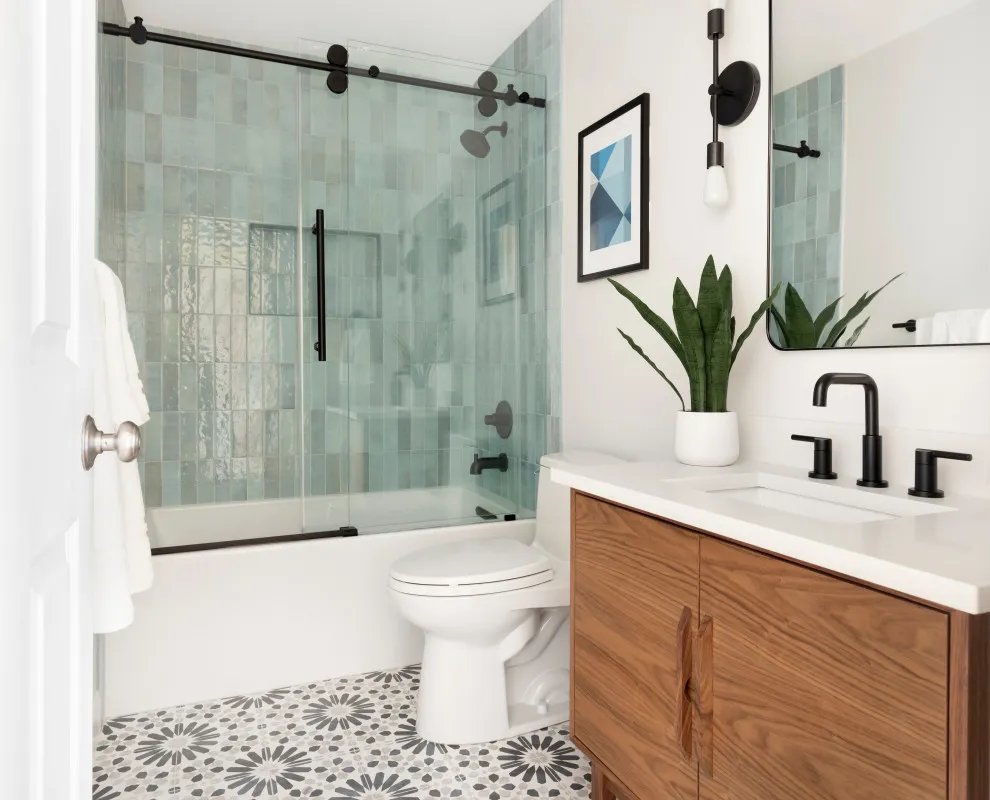 Black-and-white floral floor tiles sit beside a timber vanity and pale green shower tile