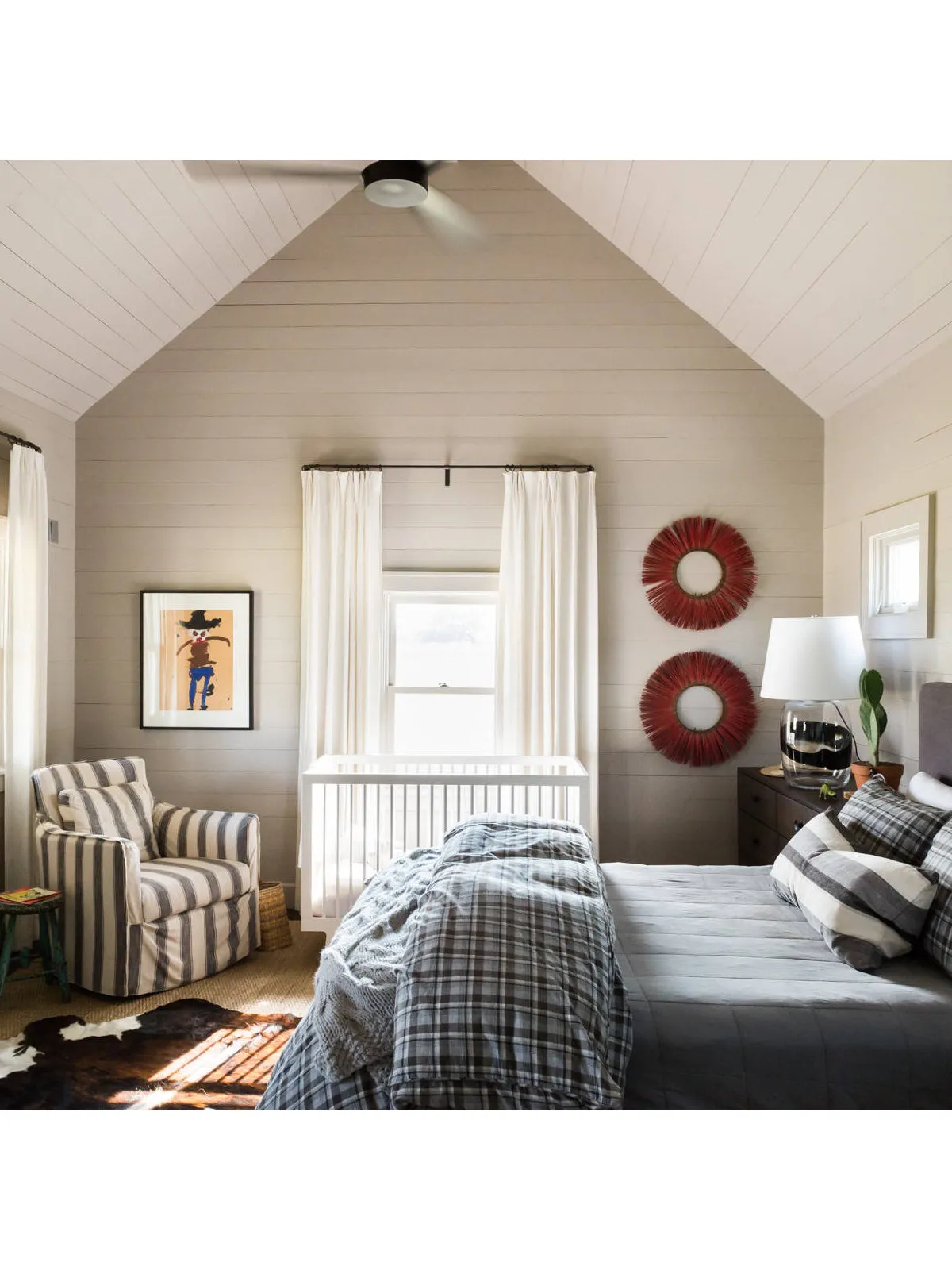 A bed occupies a compact room beneath a pitched ceiling, with a chair near the window.
