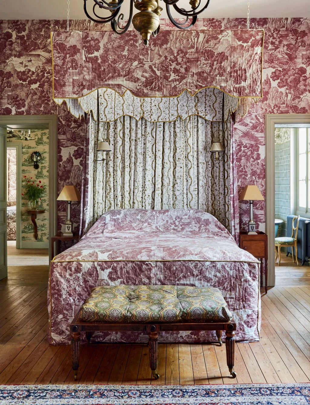 Bedroom with red-and-cream toile walls and bed covering, a fabric canopy and a patterned bench