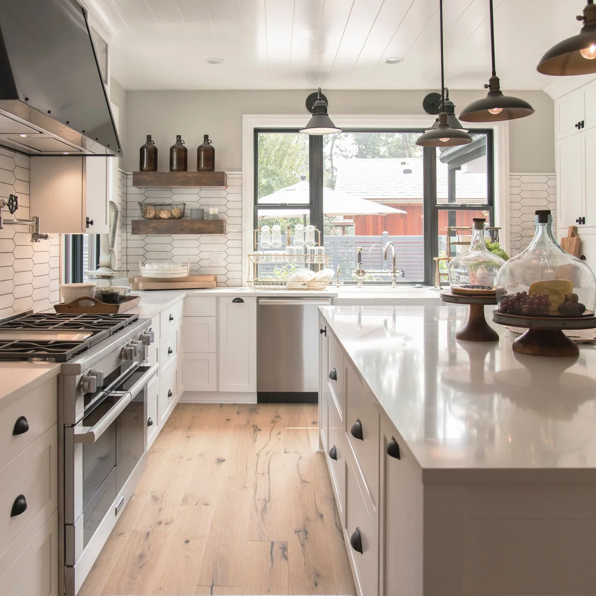 White plank ceiling over a compact white kitchen with dark hanging lights