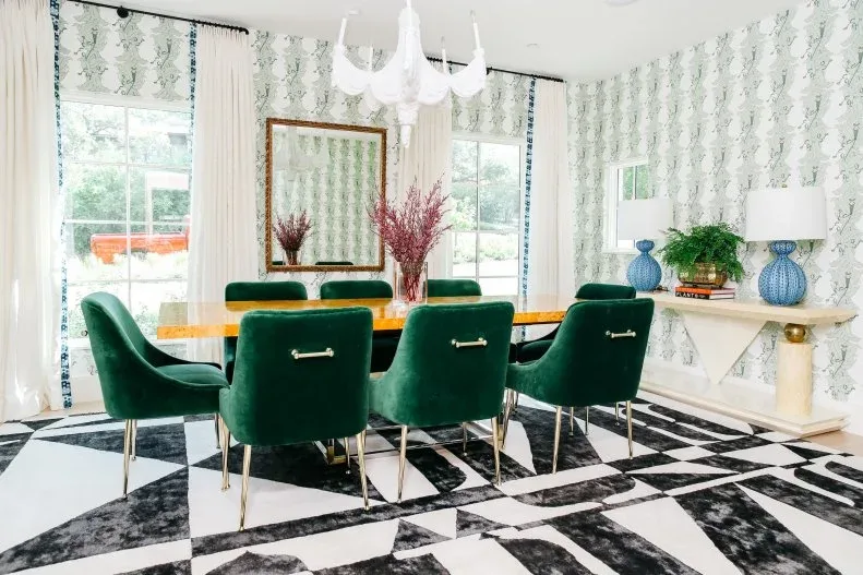 Green upholstered dining chairs with gold-toned legs around a yellow-toned table above a black-and-white floor.