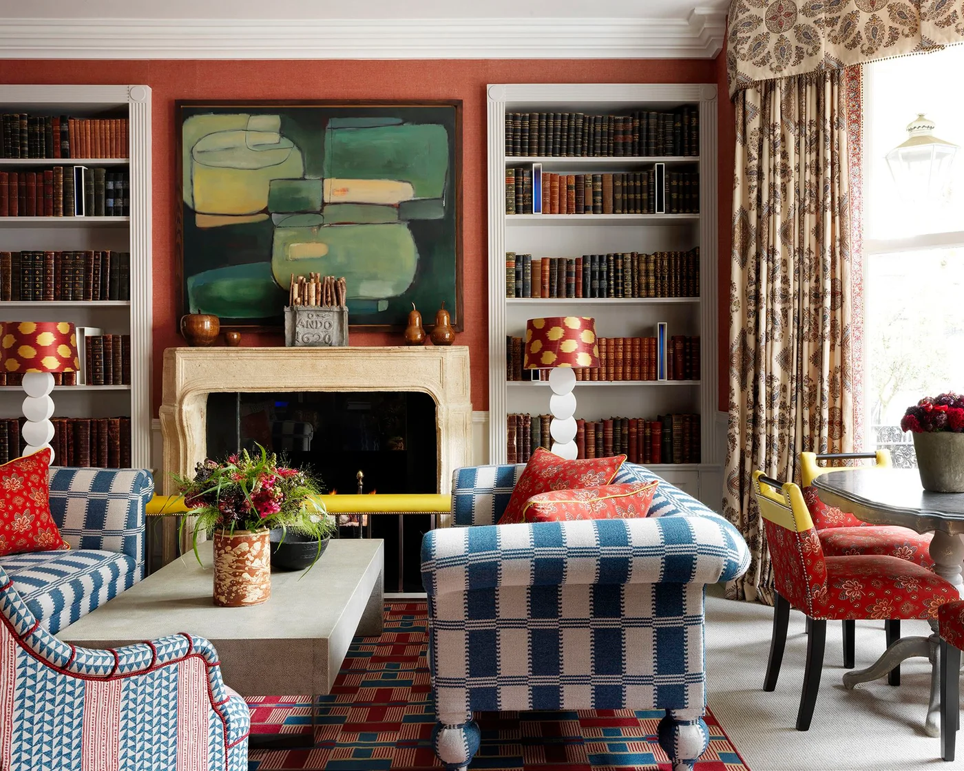 Plain rectangular coffee table with a patterned vase and dark bowl among colorful chairs