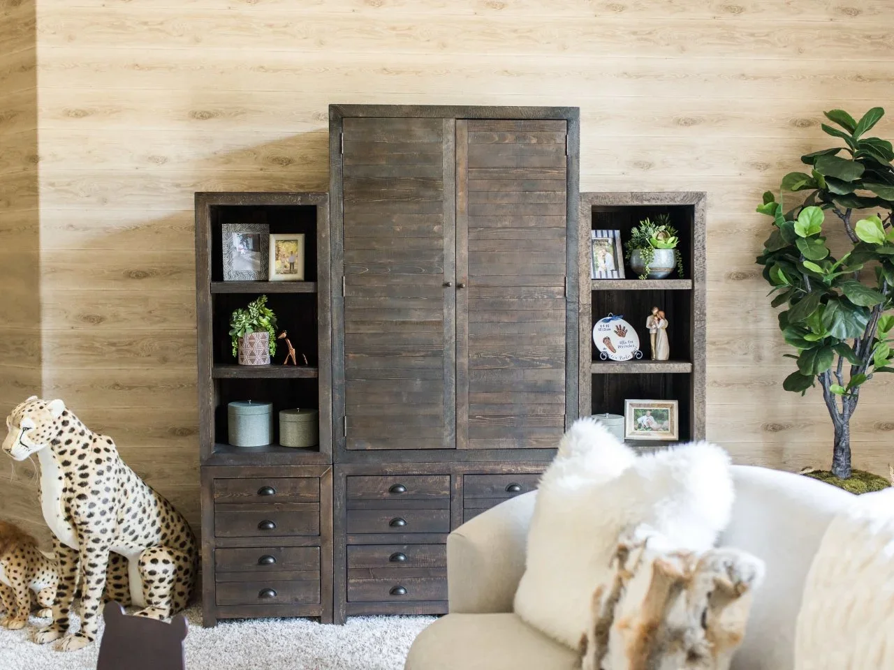 A dark timber cabinet with side shelves and drawers stands beside a large spotted plush cat.