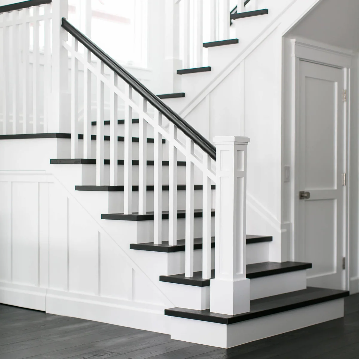 White vertical wall paneling runs beside wood steps with dark rail details.