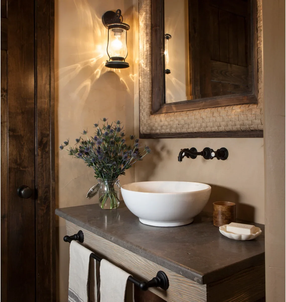 Two pale towels hang from a long dark rail across the wood front of a compact vanity with a white vessel bowl.