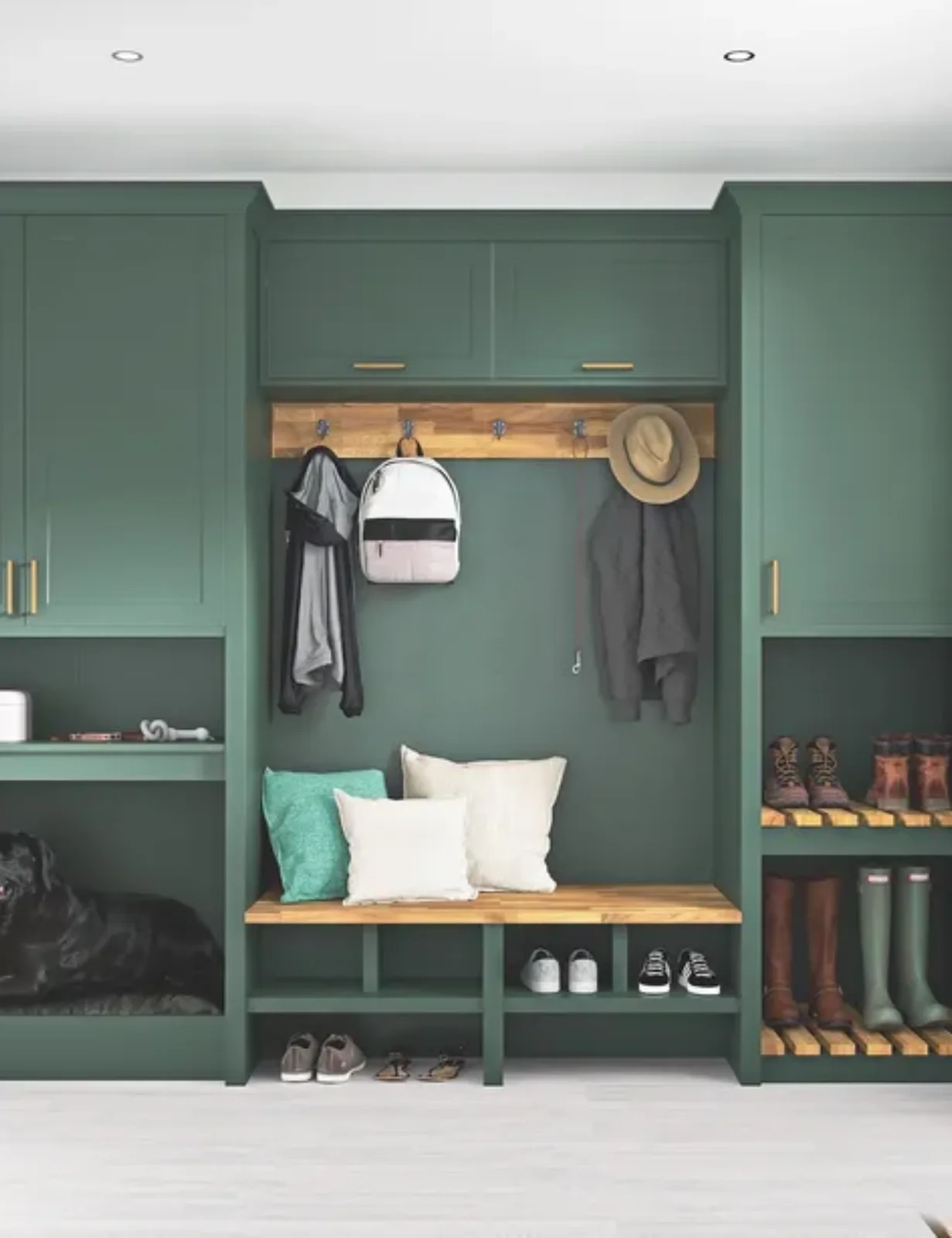 Green framed cupboards and open boot shelves surround a wood bench beneath a wood hook rail, with smaller shoe cubbies below the seat