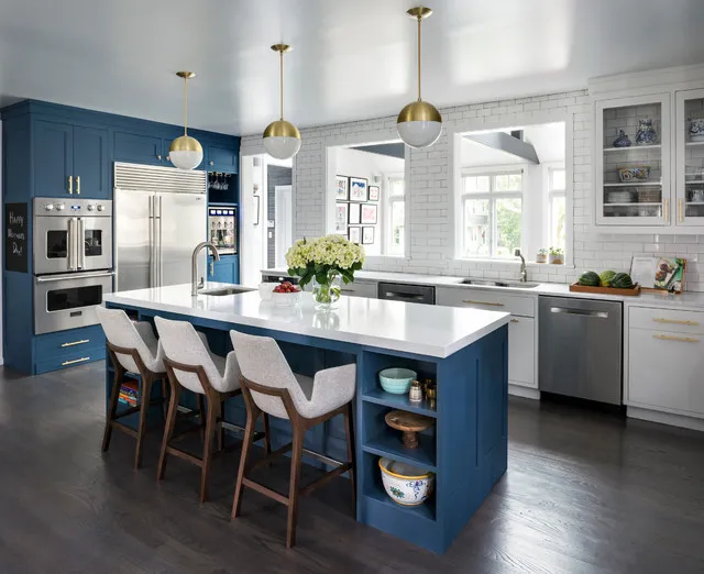 Blue cabinets and island shelving sit beside pale counters in a bright kitchen.