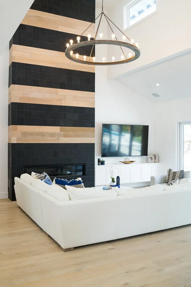 Tall fireplace chimney with alternating black and warm pale bands beside separate television and white sofa