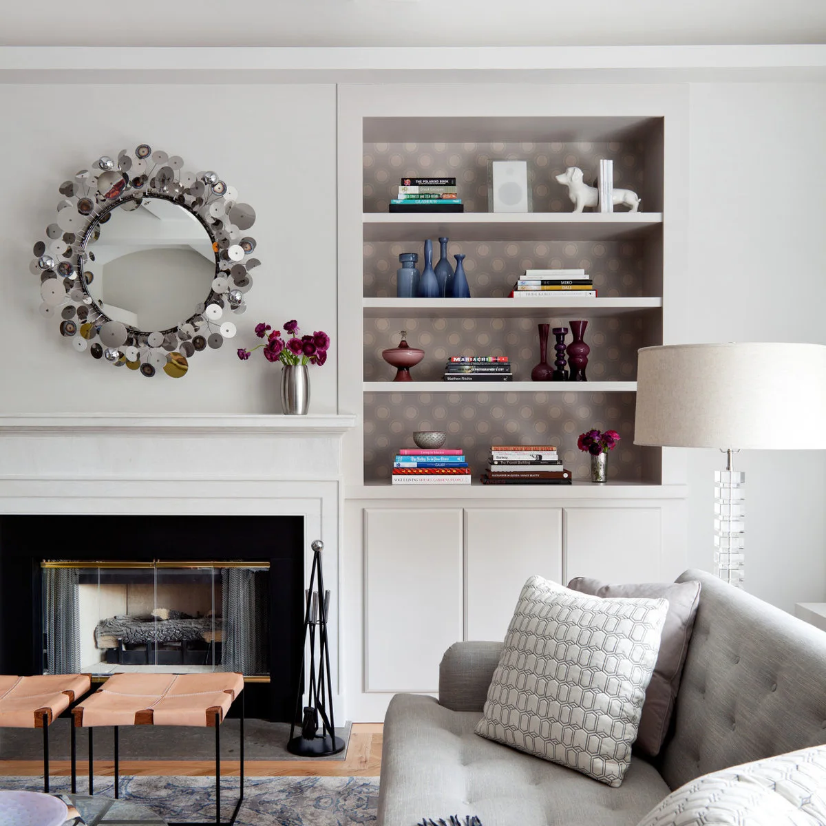 White fireplace wall and built-in cabinets with a patterned shelf back and grey seating