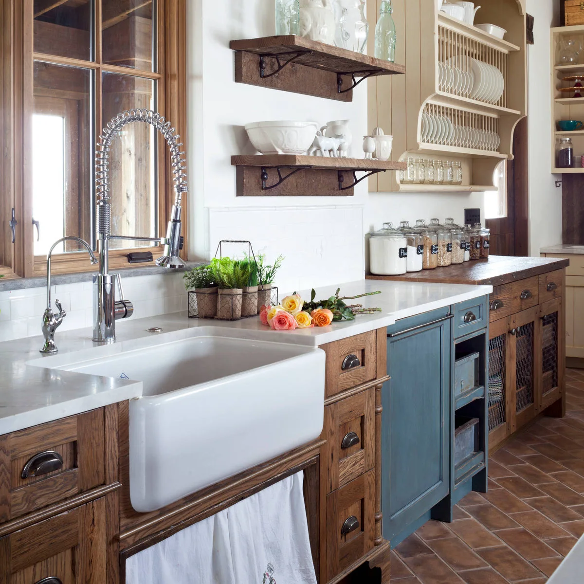 Wood shelves and a plate rack beside a wood-framed sink window above a white apron-front basin.