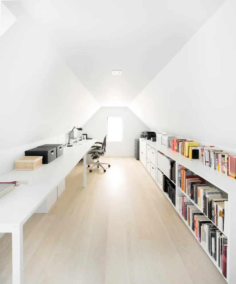 Low shelves and pale work surfaces line a bright narrow roof space