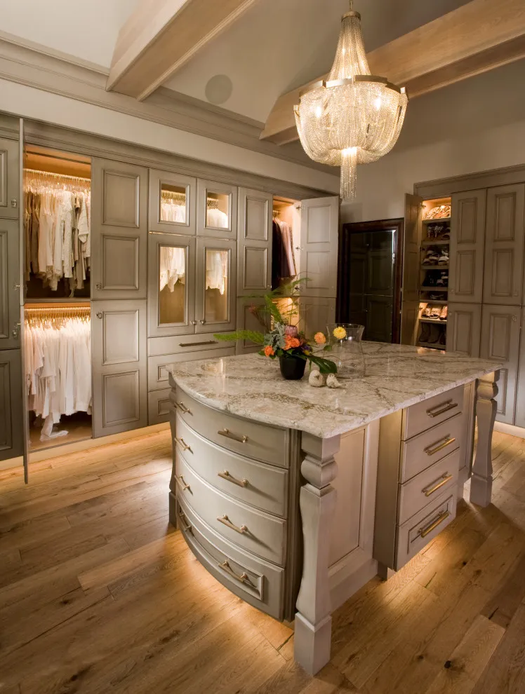 Taupe paneled cabinets surround a rounded island beneath dark timber beams