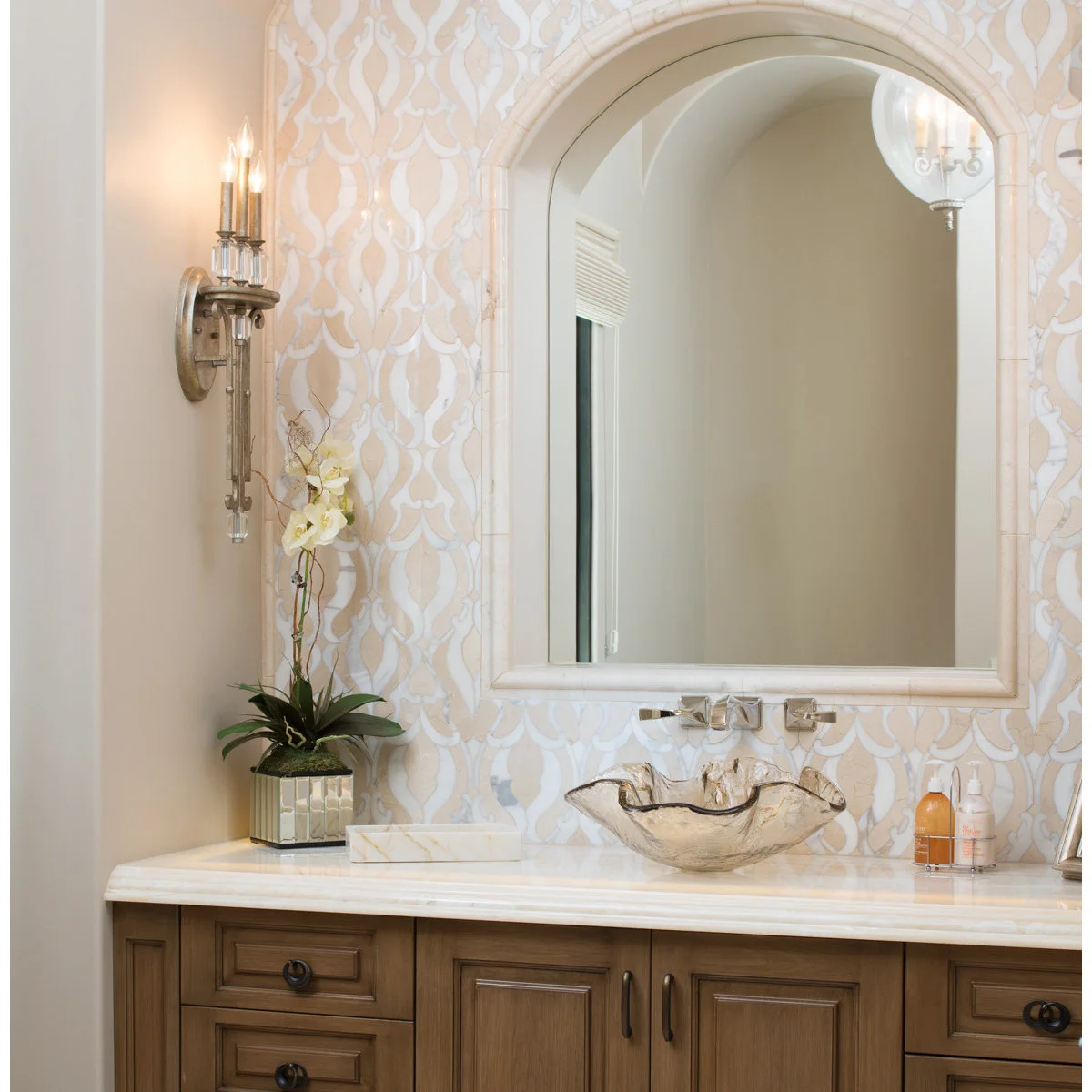 Cream arched mirror above a scalloped vessel sink and patterned bathroom wall