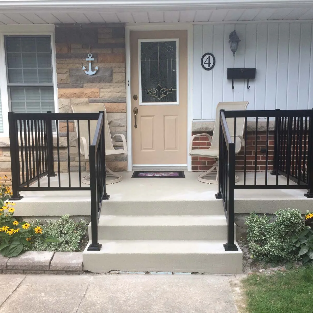 Compact front landing with a chair on each side of the door and black railings beside the steps