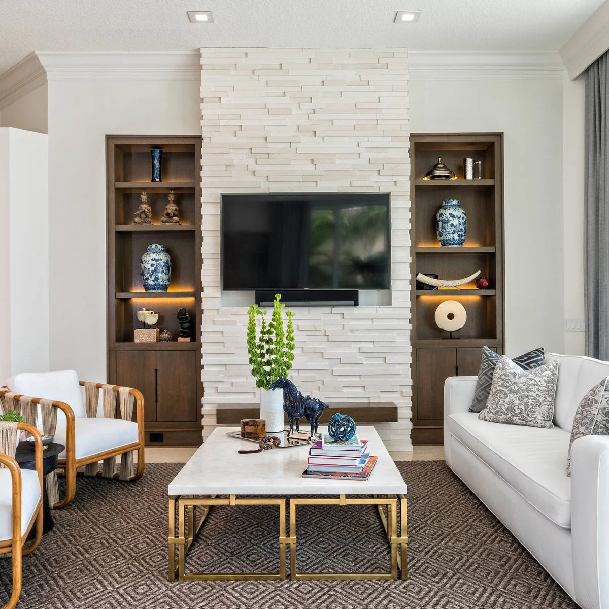 TV within a pale textured wall panel flanked by dark wood-toned display shelves