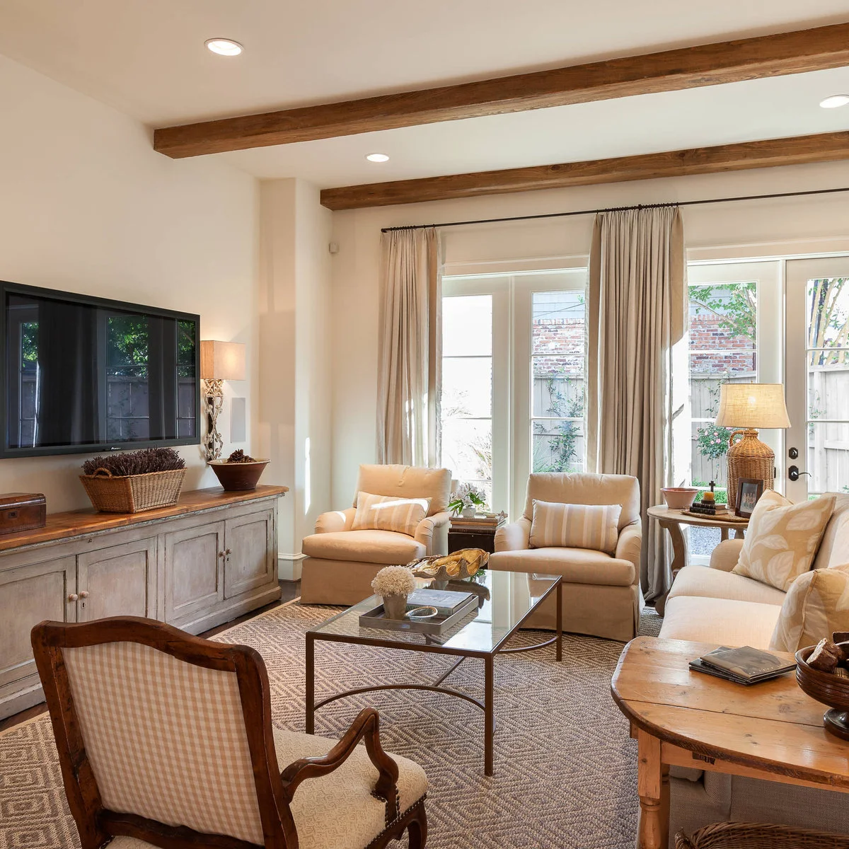 A woven basket, small box and bowl sit on a pale paneled sideboard with a wood top beneath a television.