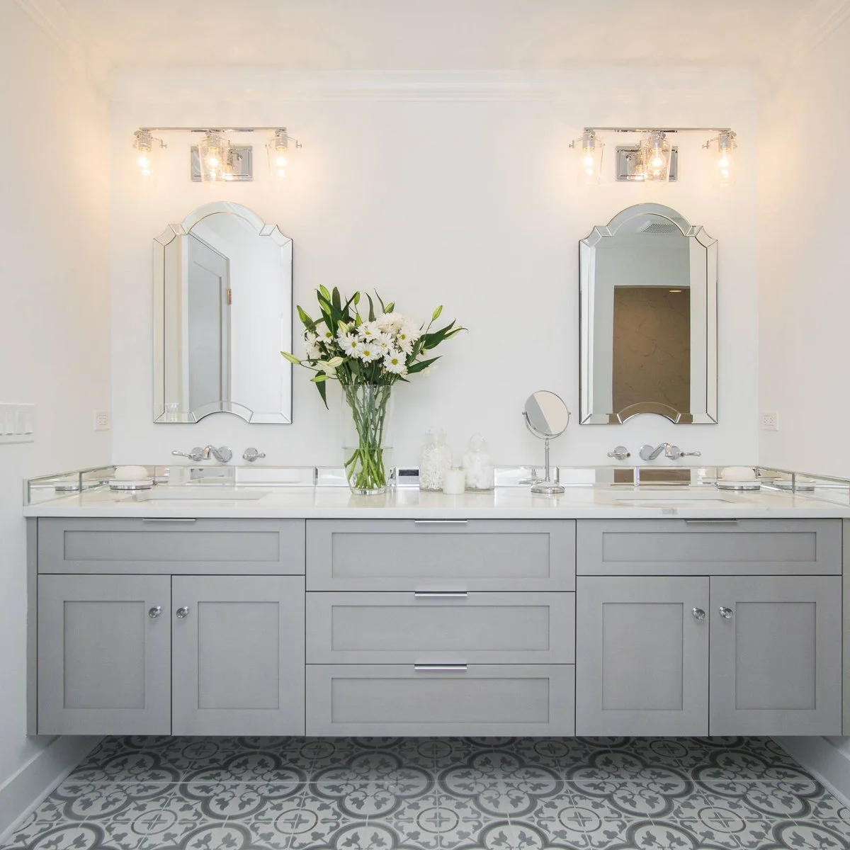Two decorative beveled mirrors above a pale gray double bathroom vanity