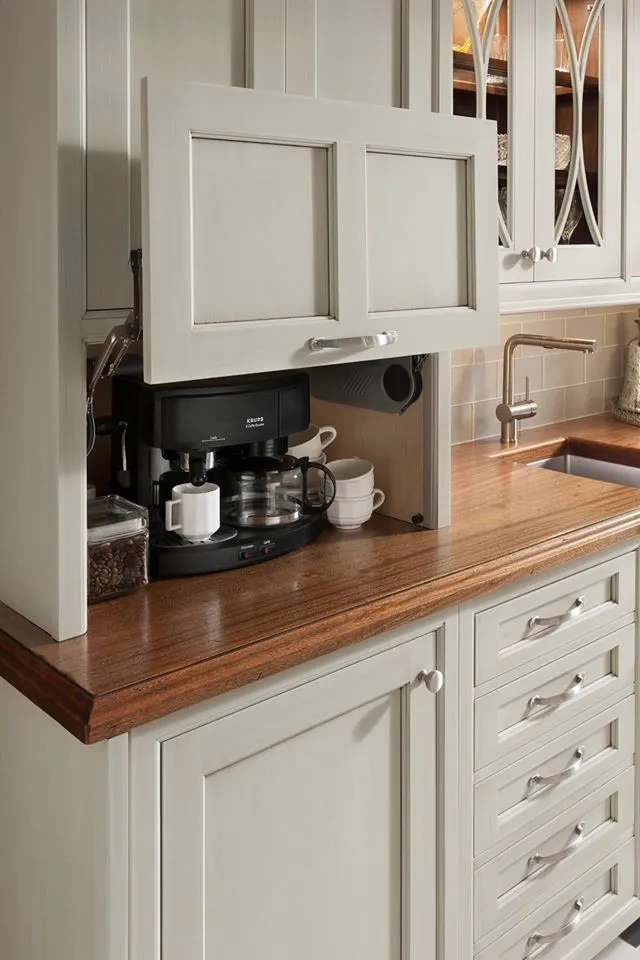 A beige cabinet above a timber counter conceals a small coffee station