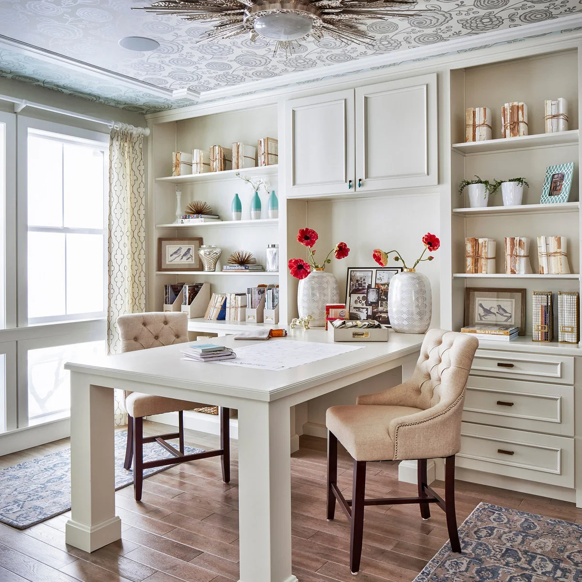Tall white worktable with two upholstered high chairs and fitted shelves and drawers behind