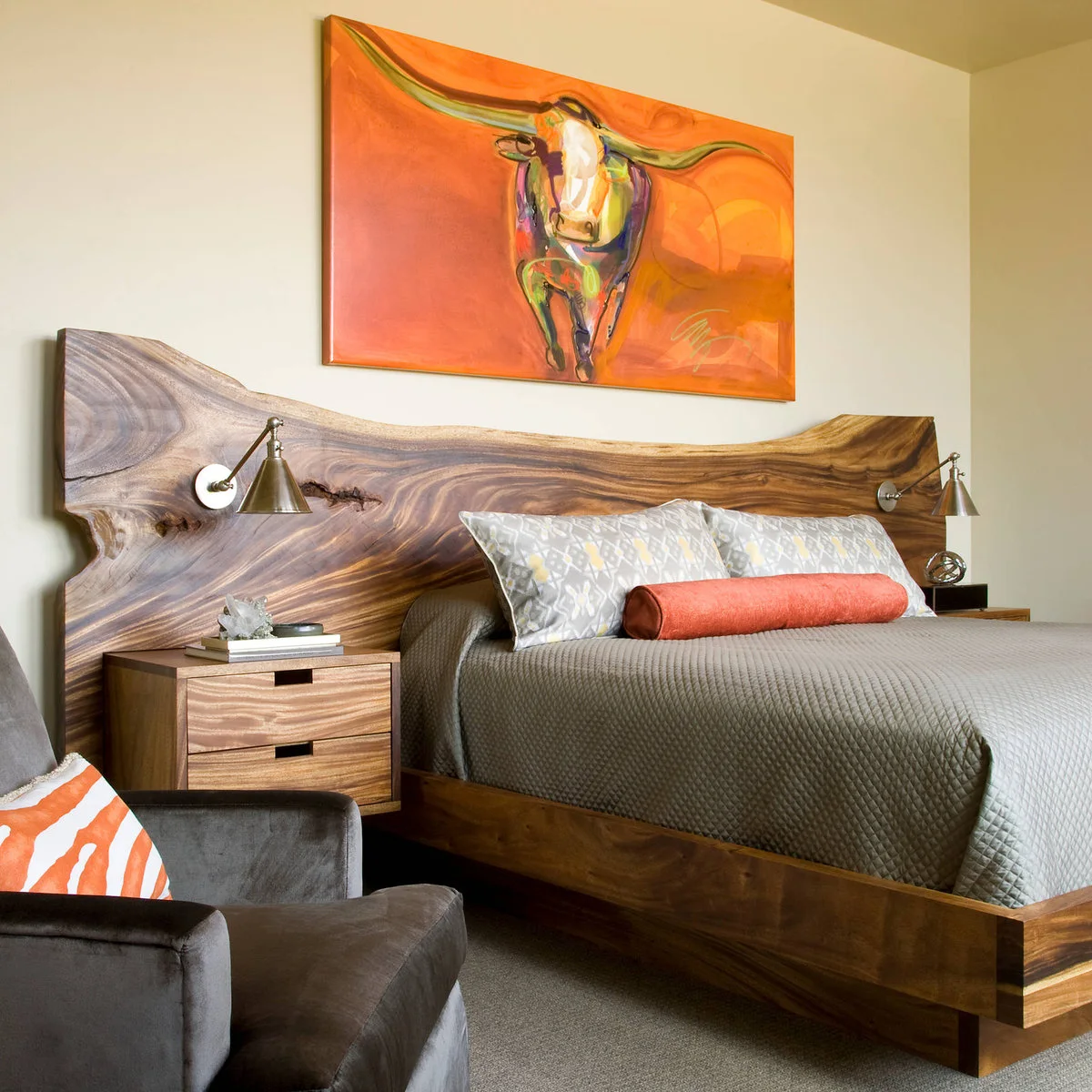 Bedroom with a broad curved wood headboard, gray bedding and a bright orange longhorn painting above