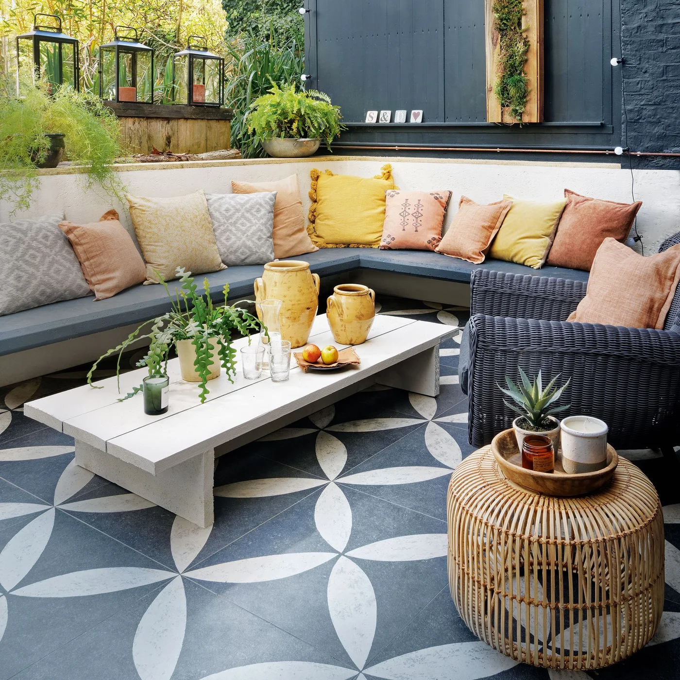 Patterned gray-and-white paving sits beneath corner seating with yellow and pink cushions
