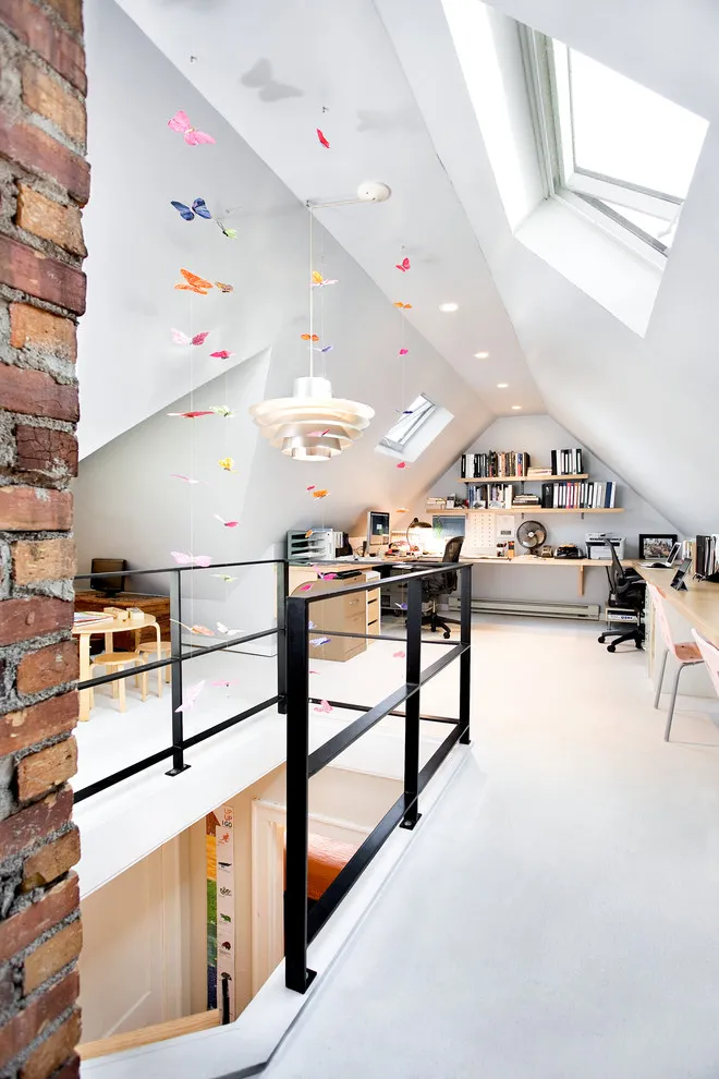 An attic workspace with roof windows sits beyond a stair opening and dark rail