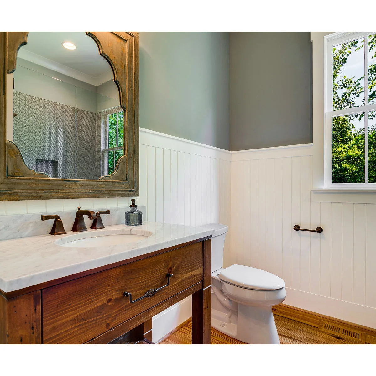 White vertical grooved bathroom paneling beneath a pale gray wall and wood-framed mirror