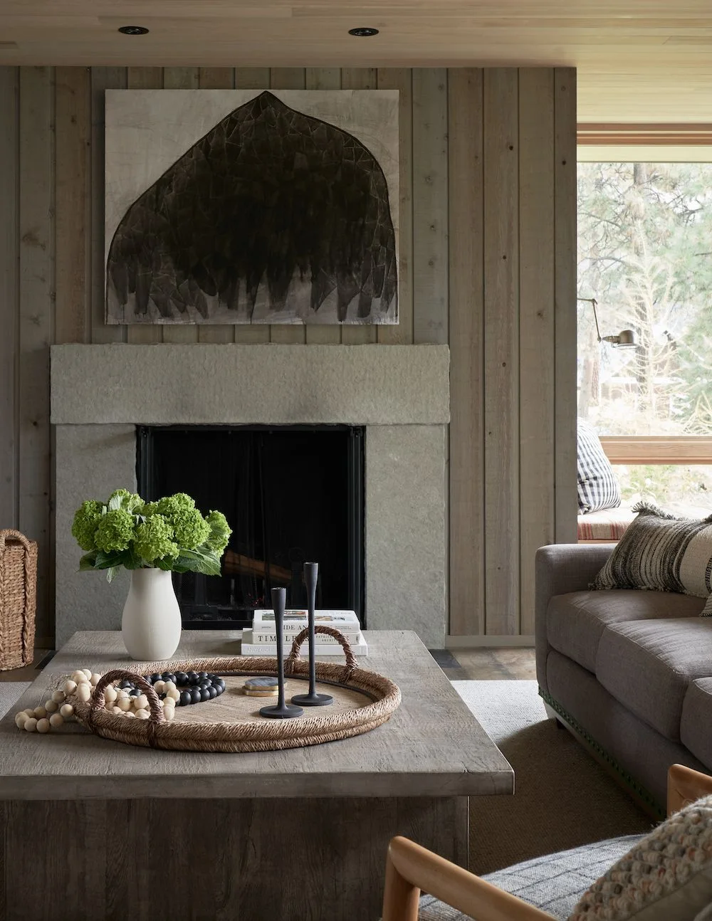 A pale rectangular fireplace surround sits against vertical timber boards behind a timber coffee table.