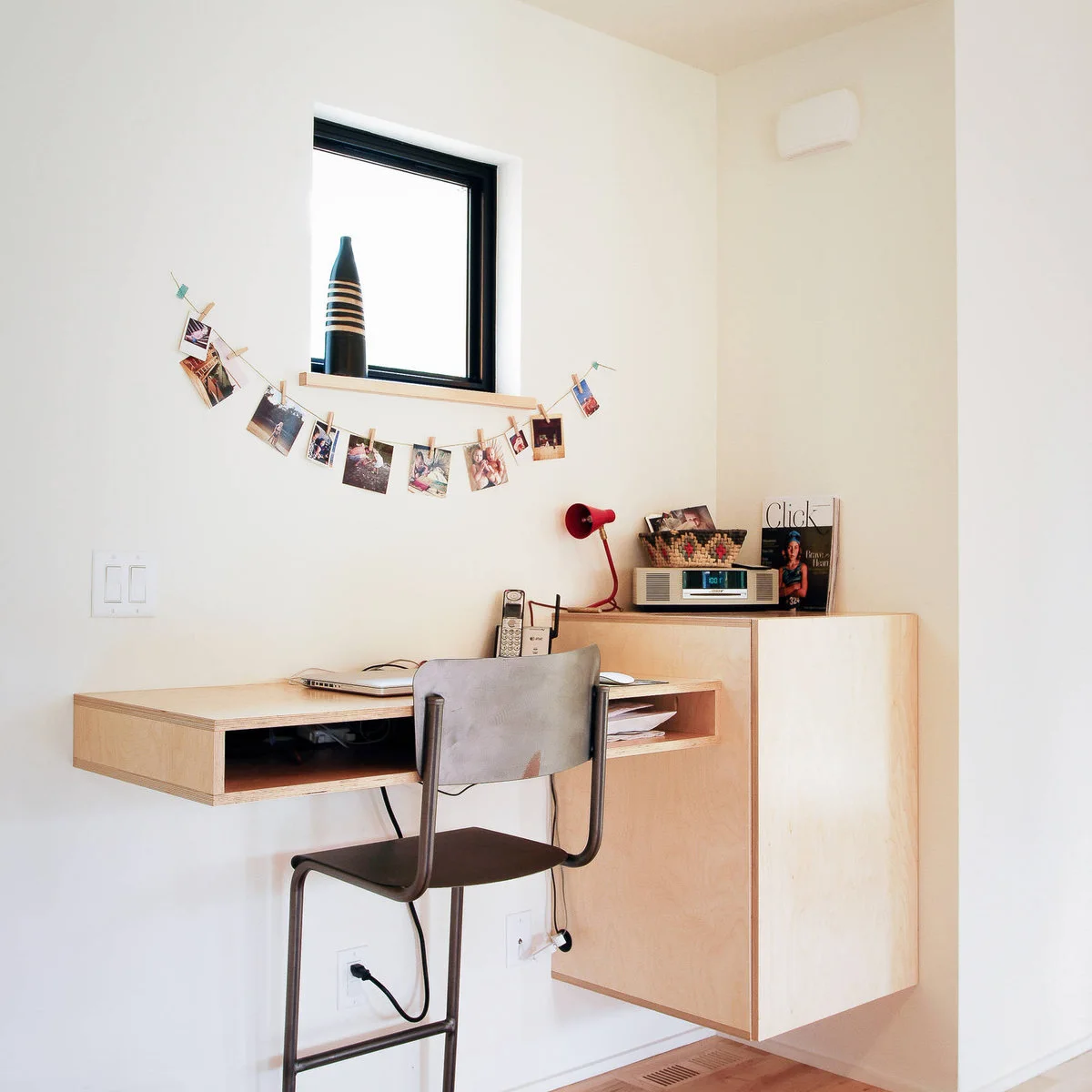 Wall-mounted wood desk with an open paper slot, adjoining cabinet and simple dark chair