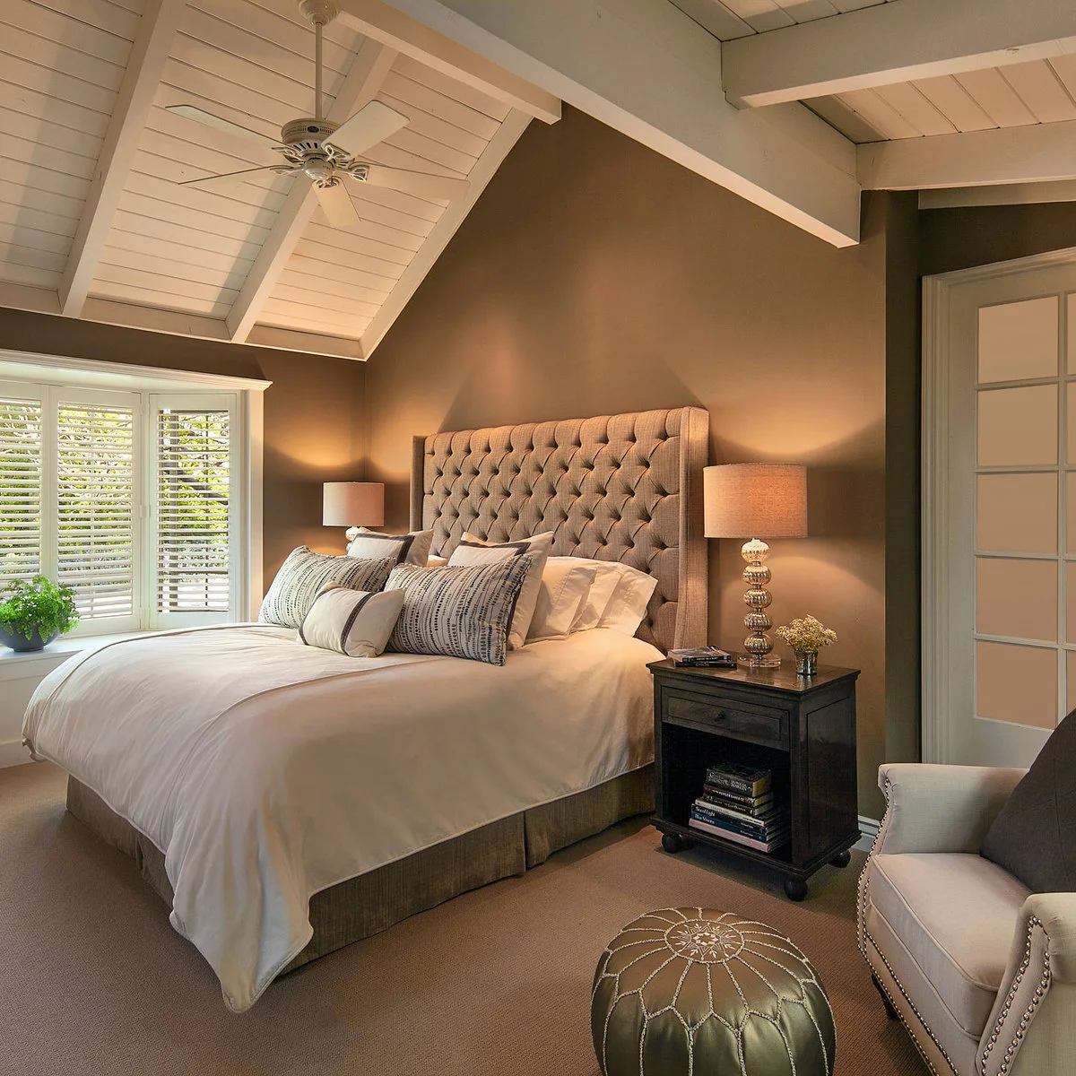 Brown-walled bedroom with tufted headboard, pale bedding and matching bedside lamps