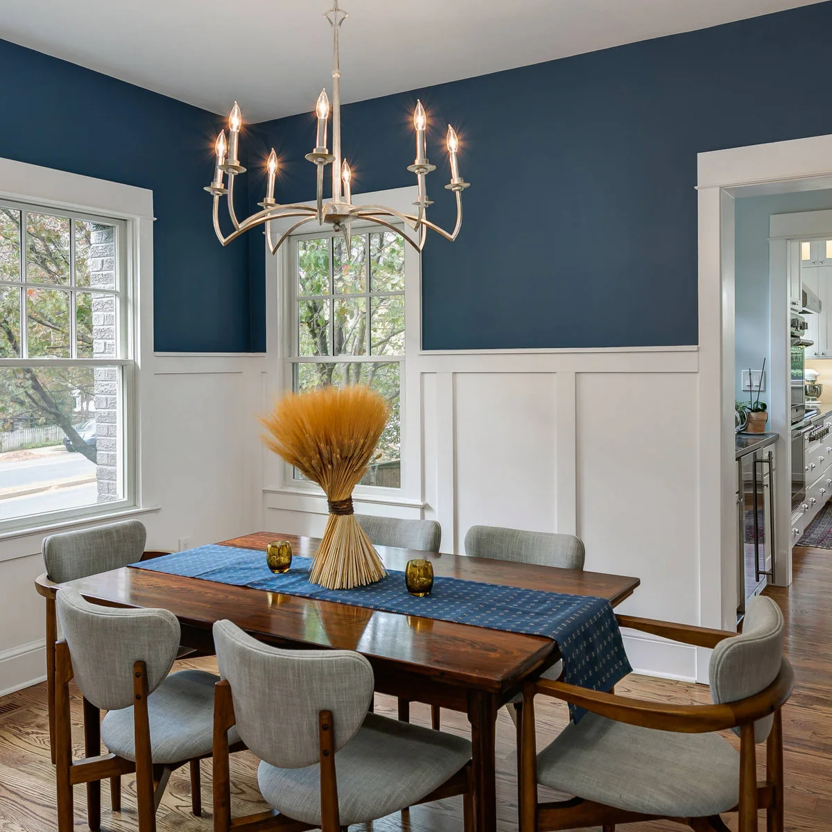 White lower wall paneling beneath dark blue dining-room walls and a wood table