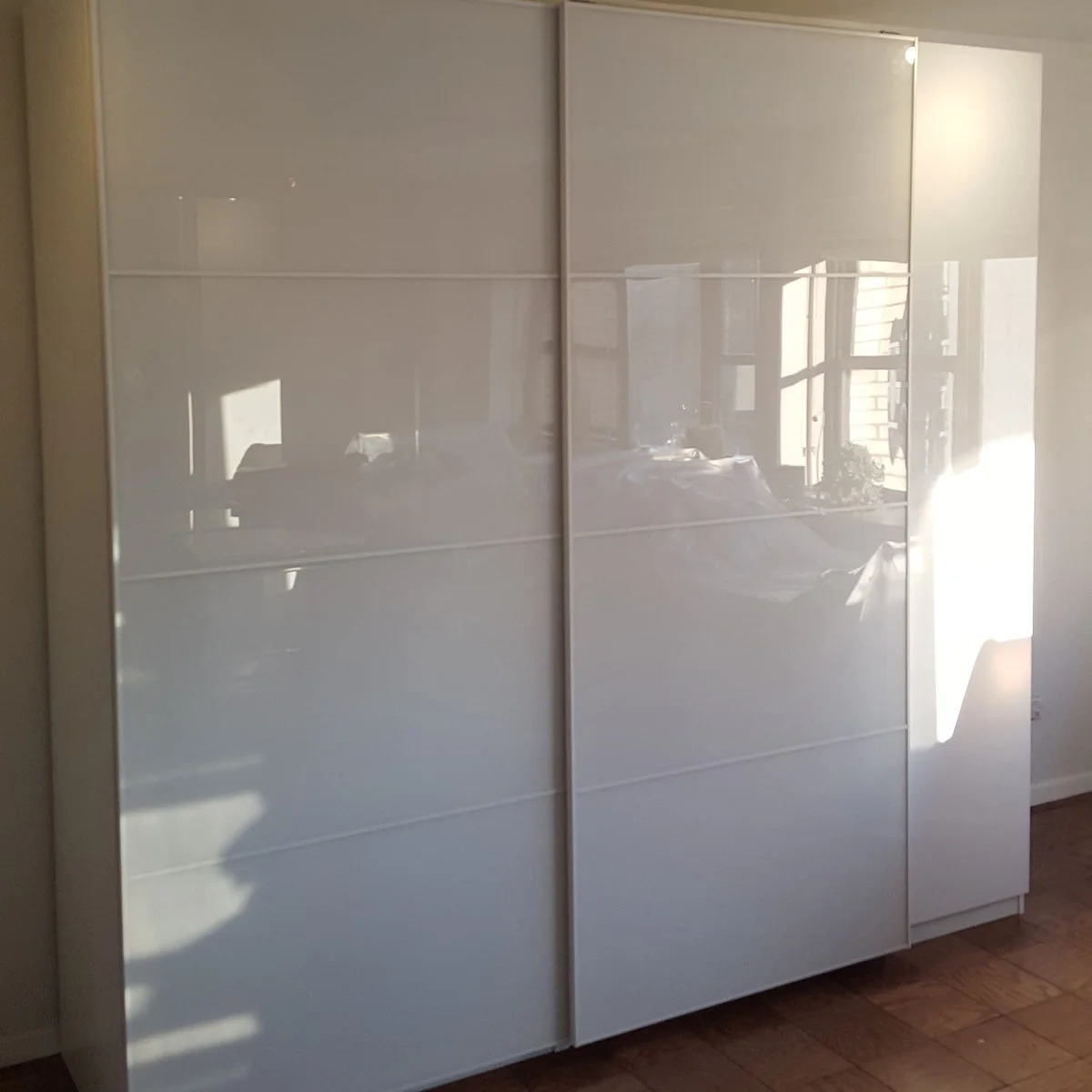 White PAX wardrobe with glossy sliding panels and horizontal divisions