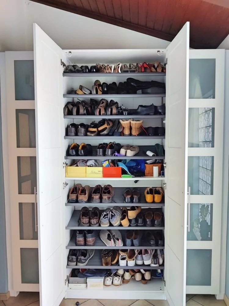 White PAX cabinet filled with pairs of shoes on closely spaced shelves behind open doors