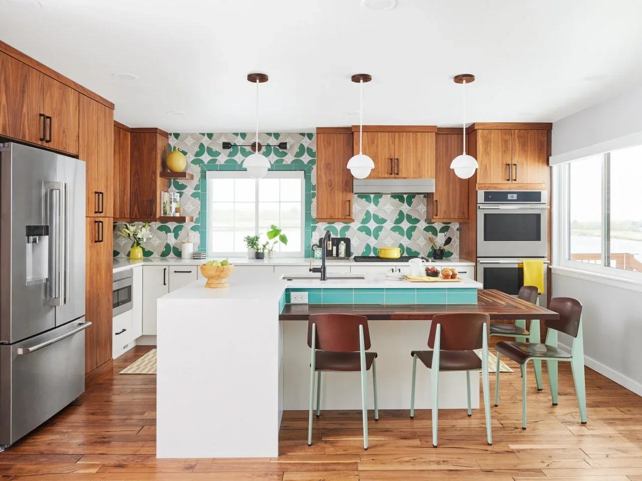 Walnut upper and tall cupboards sit above white lower cabinets, with green patterned tile and a multilevel island.