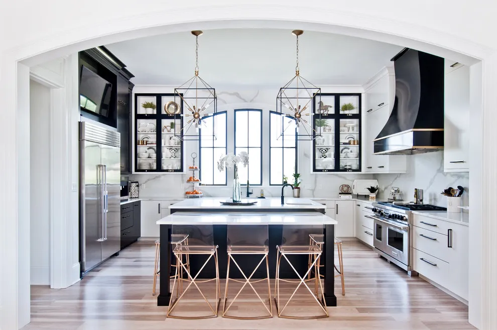 White cabinetry surrounds a dark island beneath an arched room opening