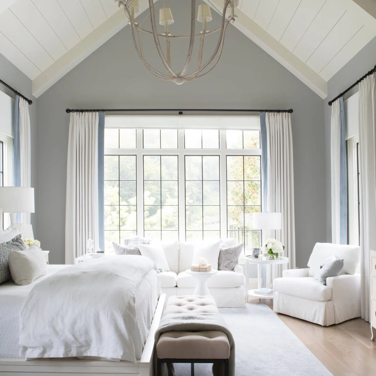 White painted plank ceiling and beam above a bed in a gray bedroom