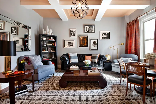 A black tufted sofa sits among pale chairs, patterned rugs and collected pictures.