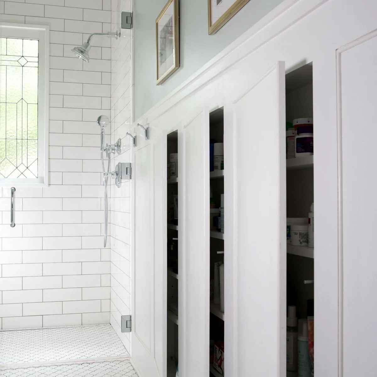 Several narrow recessed cupboards with toiletries behind white panel doors