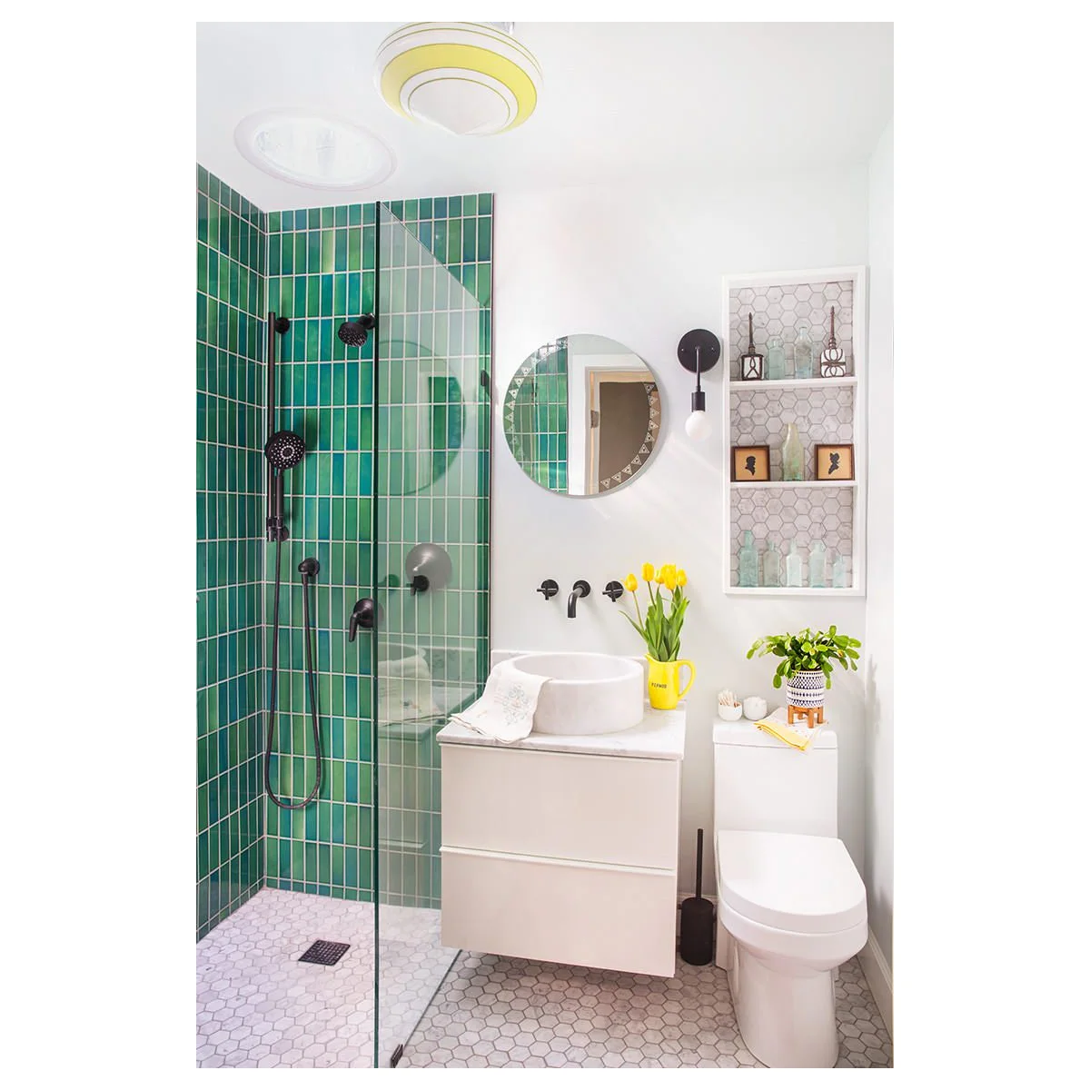 Small bathroom with vertical green shower tiles, a compact white vanity and recessed display shelves