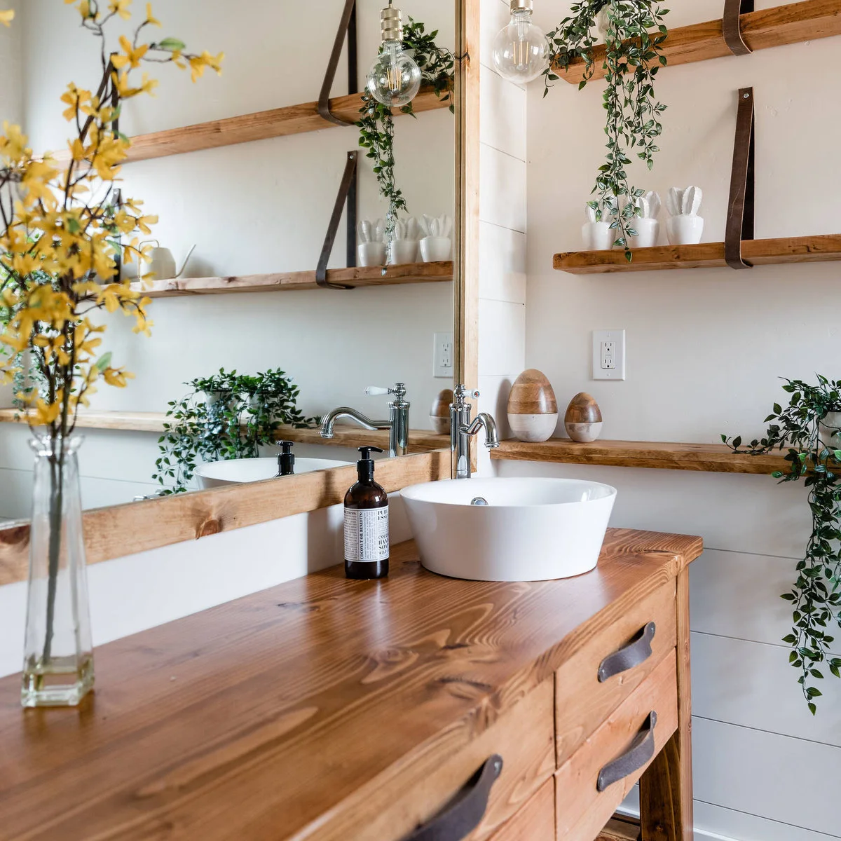 Large wood-framed mirror beside wooden shelves and a white vessel sink