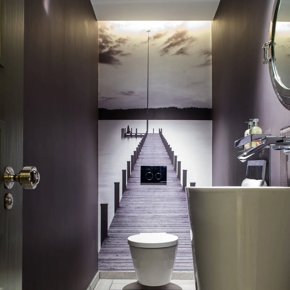 Photographic pier mural behind a toilet in a narrow powder room