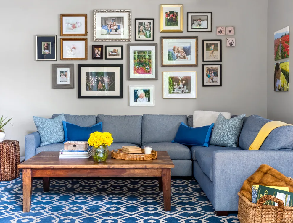 A large collection of mixed frames hangs above a blue-gray sectional