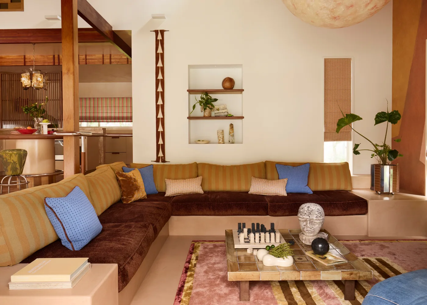 Low built-in seating with brown seat cushions, striped back cushions, blue pillows and a square tiled table.