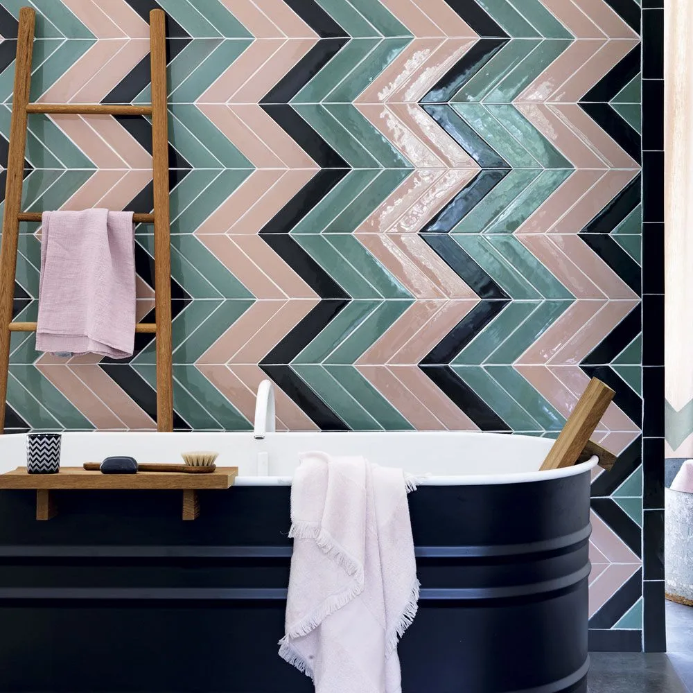 A navy ribbed bath sits in front of chevron tiles in pink, muted green and dark blue