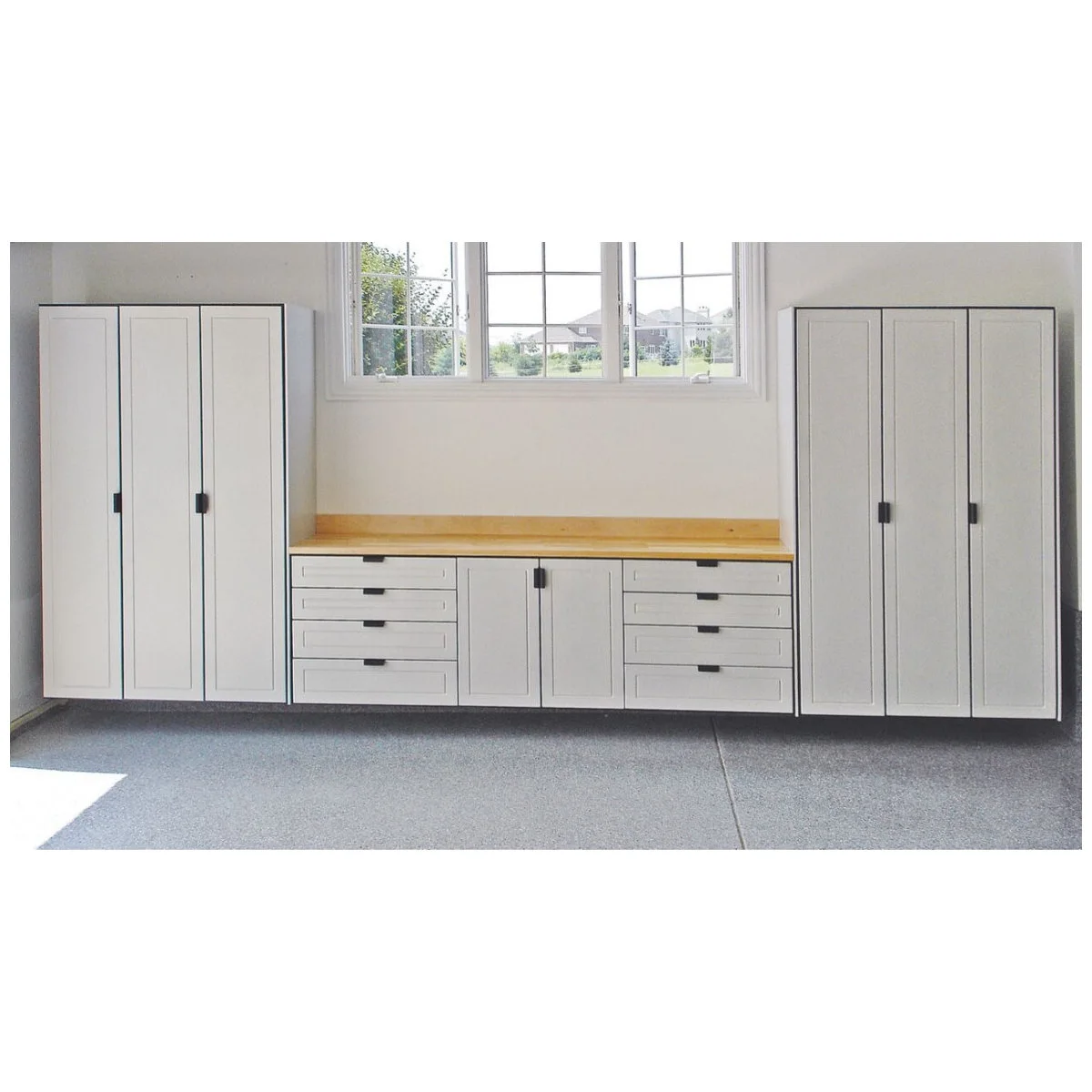 Garage workshop wall with a pale worktop, shallow drawer banks and tall white cabinets at each end.