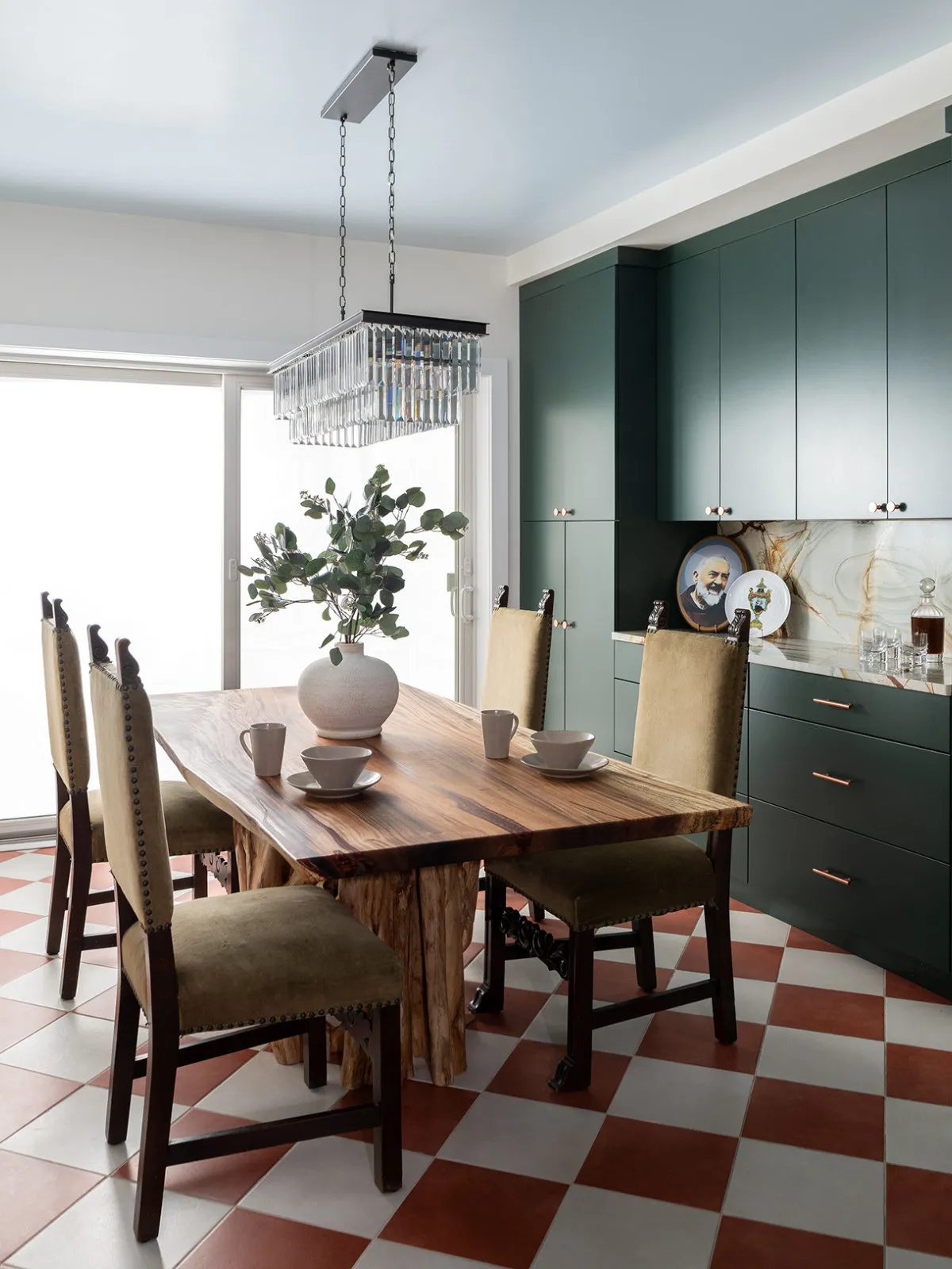 A warm timber table sits beside deep green cabinetry above a red-and-white checked floor.
