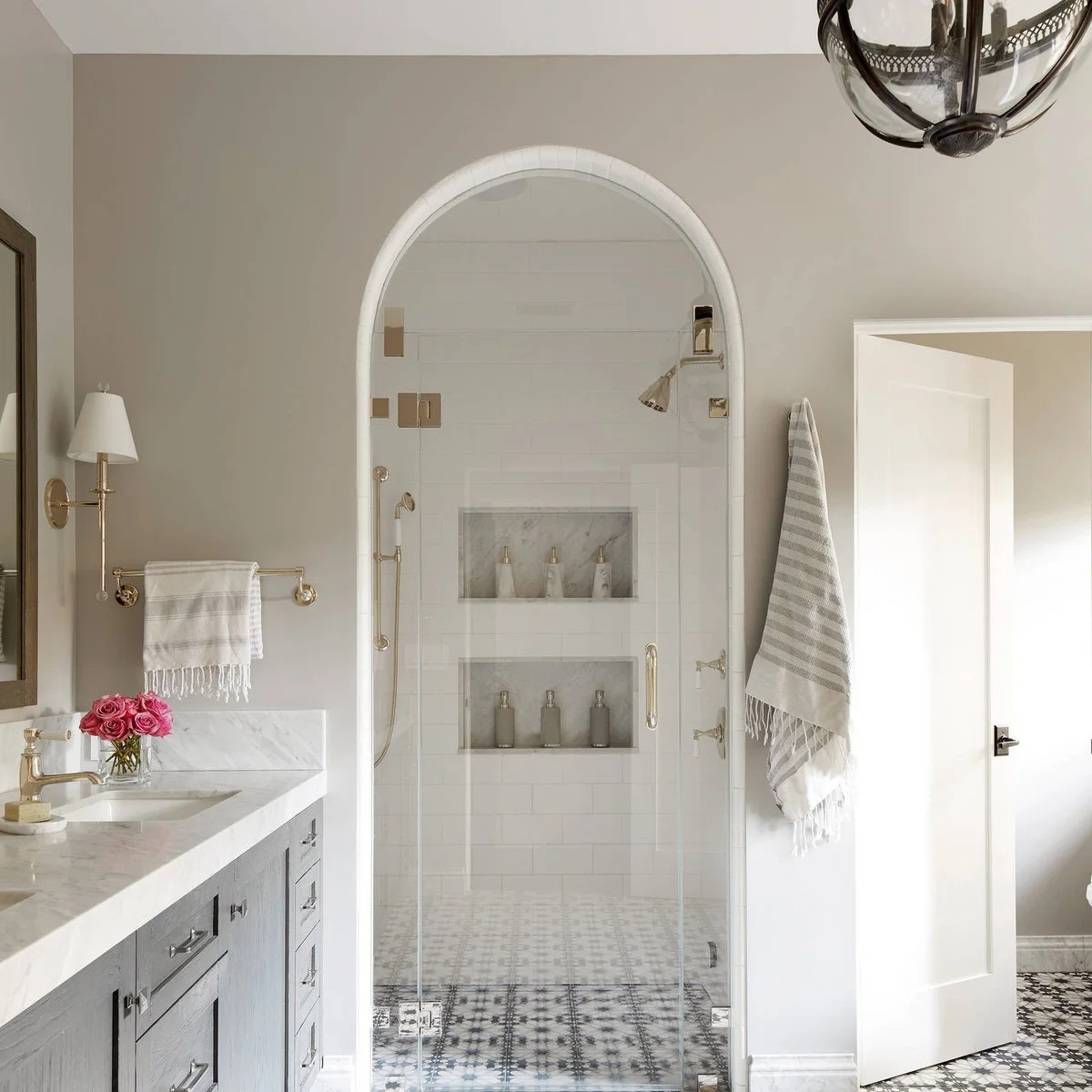 Bathroom with a white arched shower opening, two recessed niches and a black-and-white patterned floor